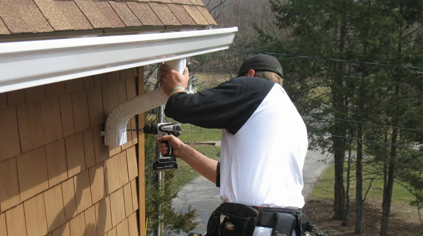 Professional contractor installing tan vinyl siding panels on a residential home exterior in Buffalo, NY
